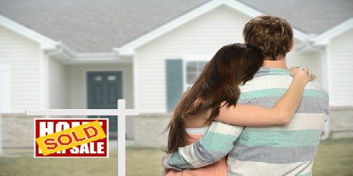 Young couple home sold sign